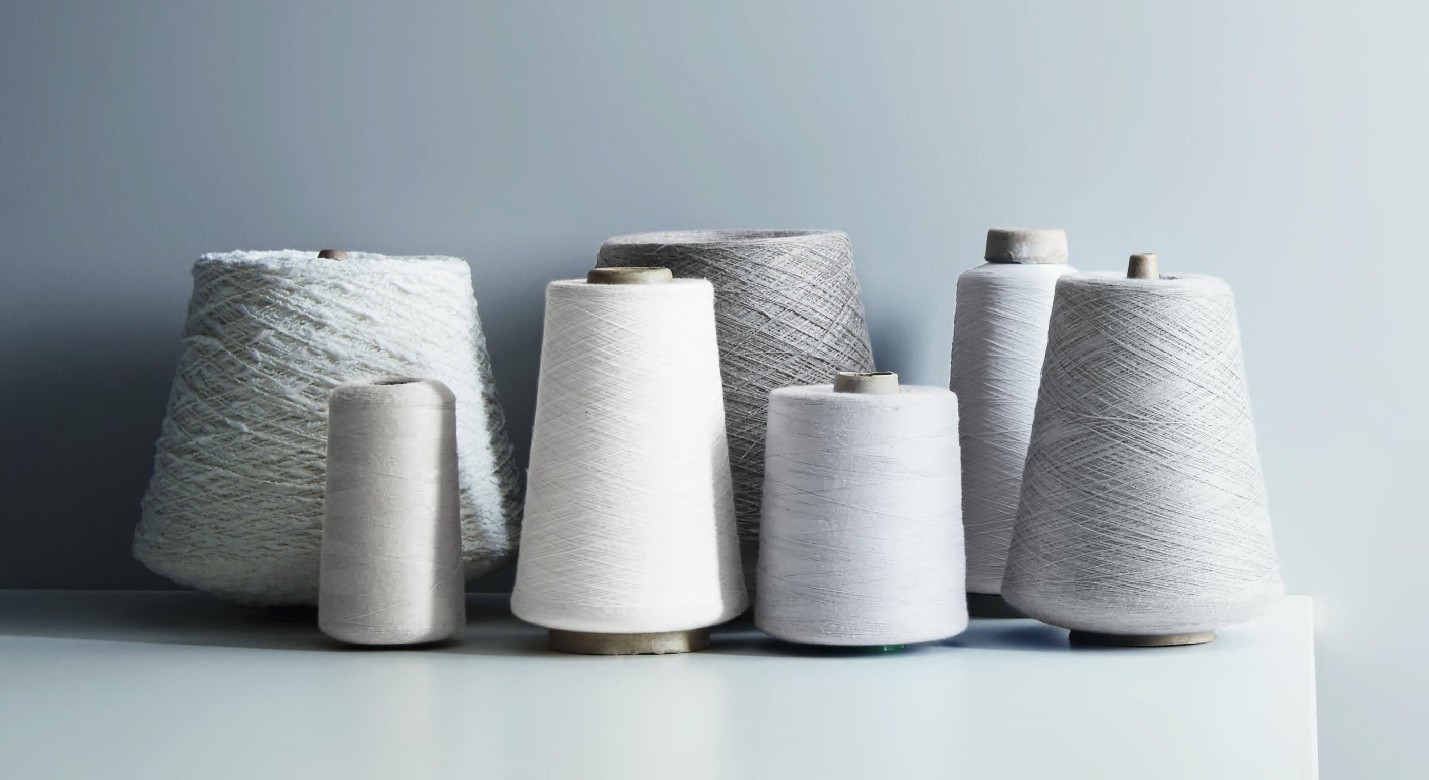 A collection of spools of thread, all different sizes in neutral grey shades